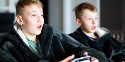 two young boys sitting on a couch playing a video game