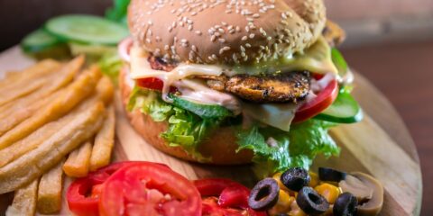 hamburger with vegetables and meat beside French fries