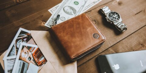 a wallet sitting on top of a wooden table next to a cell phone