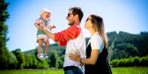 man in white and red polo shirt carrying girl in blue denim jeans during daytime