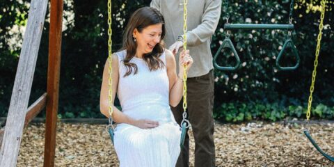 Pregnant woman enjoys a swing with her partner.