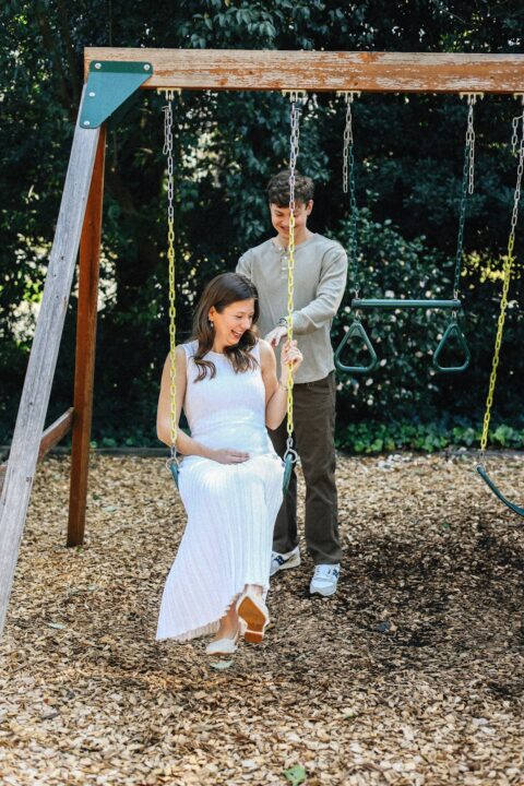 Pregnant woman enjoys a swing with her partner.