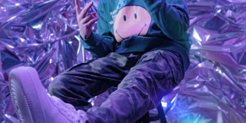 a man sitting on a stool with a cell phone in his hand