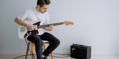 man in white crew neck t-shirt playing electric guitar