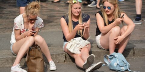 3 women sitting on gray concrete floor during daytime