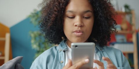 Young woman looking at smartphone screen of smartphone.