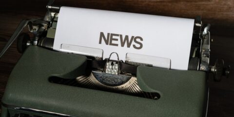 a close up of a typewriter with news paper on it