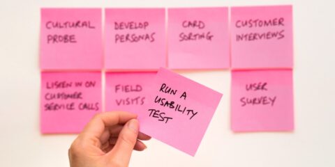 person holding pink sticky note