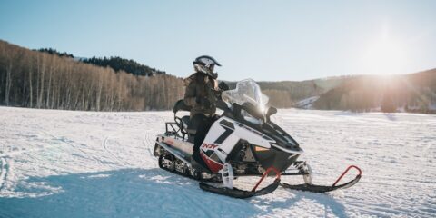 person riding on white and black snowmobile during daytime