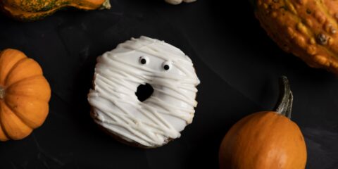 a black surface with pumpkins, gourds, and a doughnut