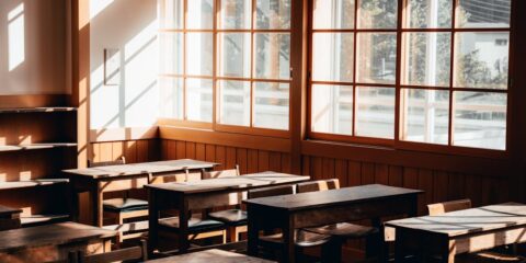 an empty classroom with wooden desks and windows