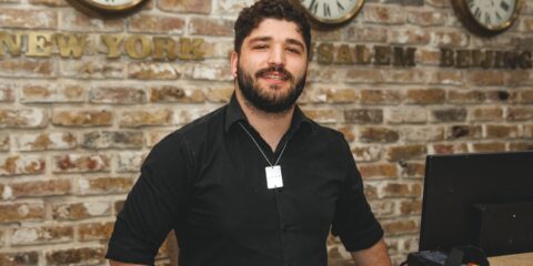 a man sitting at a desk in front of a brick wall