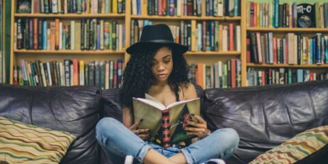 woman reading a book while sitting on black leather 3-seat couch