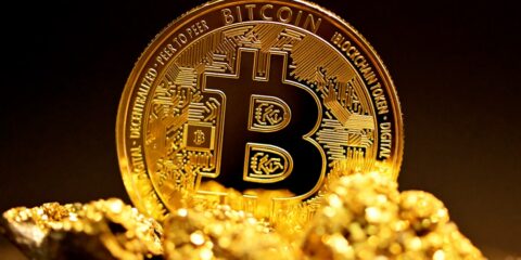 a bitcoin sitting on top of a pile of gold nuggets
