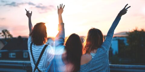 photo of three women lifting there hands