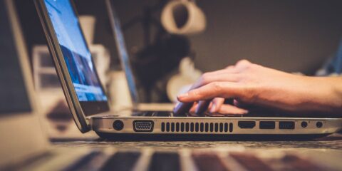 person using silver laptop computer on desk