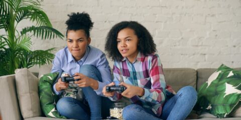 Two women playing video games on a couch.