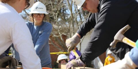 man in black jacket and white hard hat holding green plastic bottle