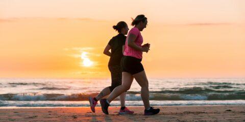 woman in black tank top and black shorts running on beach during sunset