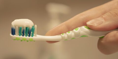 a person is holding a toothbrush with toothpaste on it