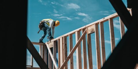 man in yellow shirt and blue denim jeans jumping on brown wooden railings under blue and
