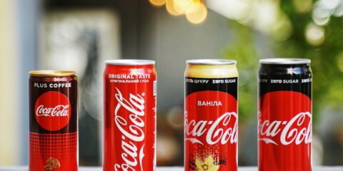 three cans of coca - cola are lined up on a ledge