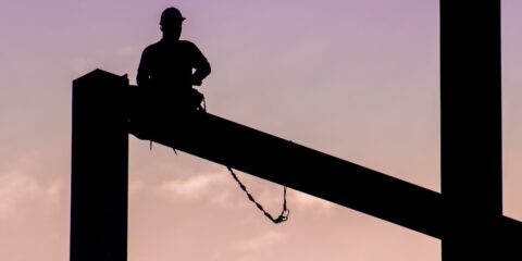 silhouette of man sitting on electric post during daytime