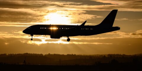 airplane flying over the city during sunset