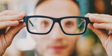 person holding eyeglasses with black frames