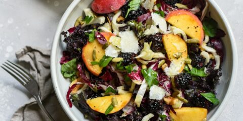 a bowl of salad next to a bowl of dressing