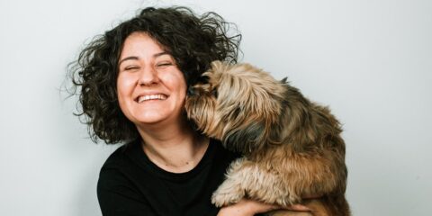 dog kissing woman in black crew-neck shirt