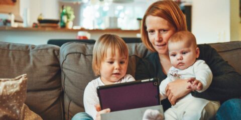 Discussion Board – Super Moms (Nationwide) – Earn $85 two babies and woman sitting on sofa while holding baby and watching on tablet
