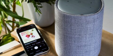 A smartphone is connected to a cylinder speaker.