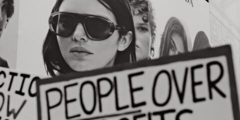 Woman holding sign people over profits