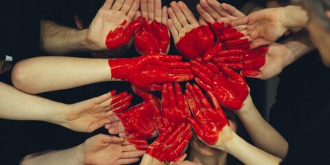hands formed together with red heart paint