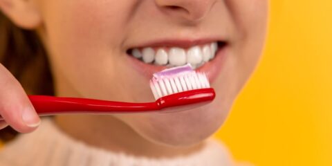 girl with red and white toothbrush in mouth