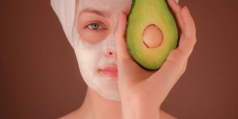 woman with white face mask holding green fruit