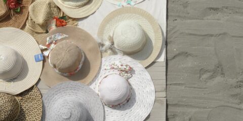 a table topped with lots of hats on top of a beach